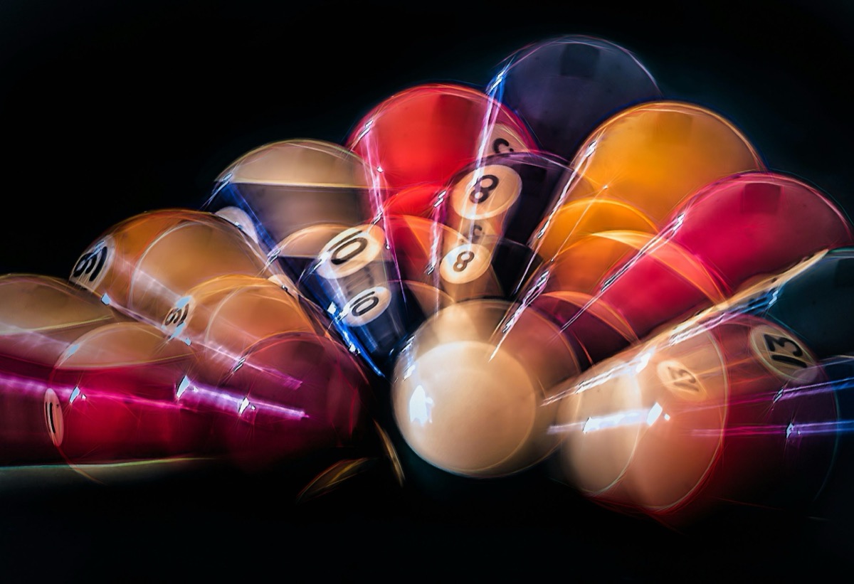 Colourful pool balls streaking with long-exposure motion trails on a dark table